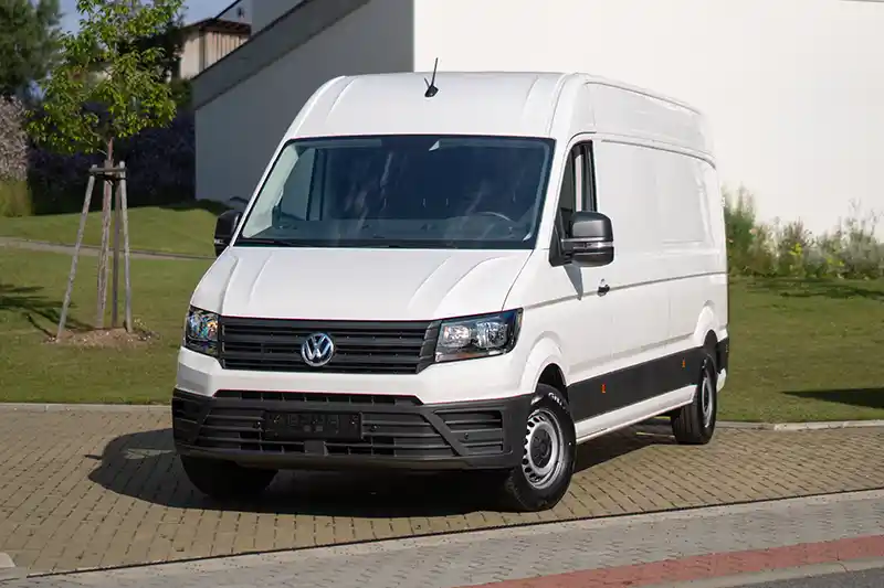 Bílá dodávka Volkswagen Crafter před budovou, autopůjčovna